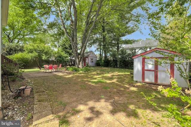 view of yard with a storage shed, an outbuilding, a fenced backyard, and a patio