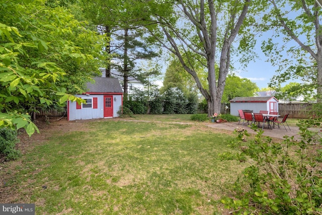 view of yard with a storage shed, an outdoor structure, a fenced backyard, and a patio area