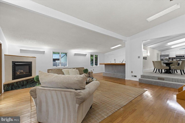 11801 Cherry Grove Dr, Gaithersburg, MD 20878 - living area with wood finished floors, vaulted ceiling with beams, a textured ceiling, visible vents, and a glass covered fireplace