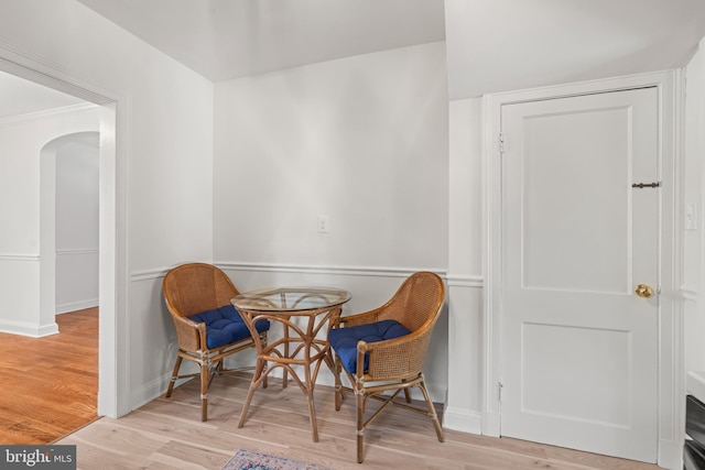 living area with baseboards, arched walkways, and wood finished floors