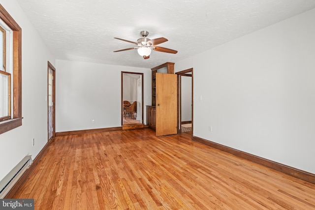 interior space featuring baseboards, a textured ceiling, light wood-style flooring, and baseboard heating