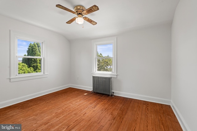 unfurnished room featuring light wood-style floors, radiator, plenty of natural light, and a ceiling fan