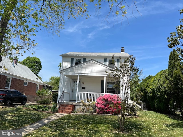 view of front facade featuring a porch, a front lawn, fence, and a chimney