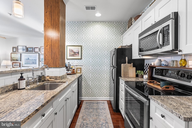 kitchen with visible vents, appliances with stainless steel finishes, a sink, baseboards, and light stone counters
