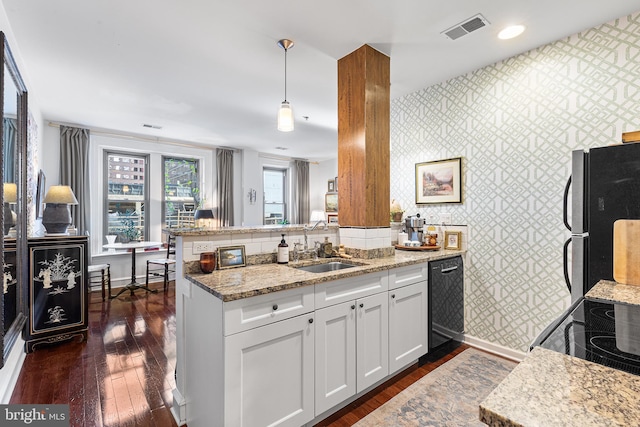 kitchen with visible vents, a sink, baseboards, black appliances, and wallpapered walls