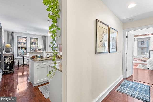 corridor featuring baseboards and dark wood-style floors