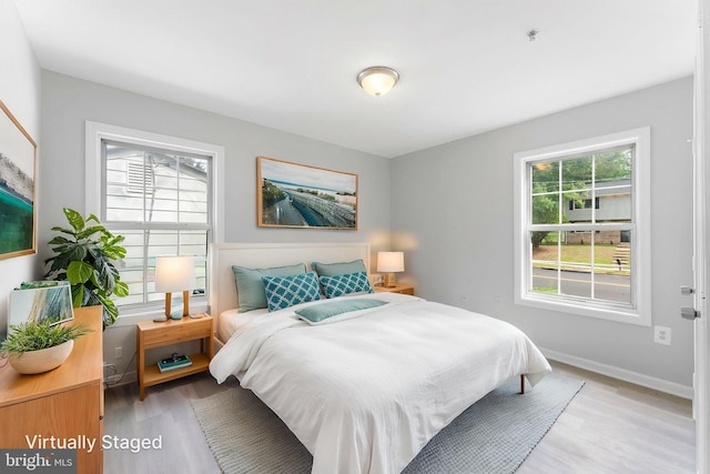 bedroom featuring multiple windows, light wood-type flooring, and baseboards