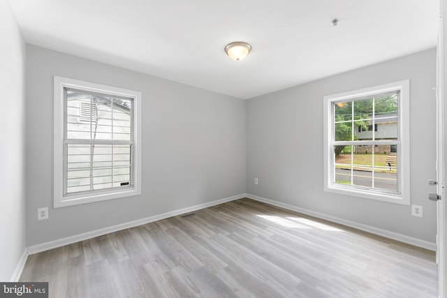 unfurnished room featuring light wood-type flooring, baseboards, and fire sprinkler in ceiling