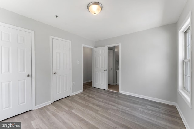 unfurnished bedroom featuring wood finished floors, baseboards, and multiple windows