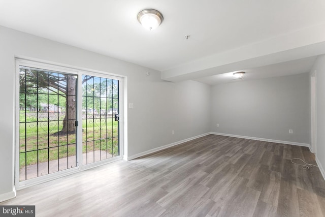 unfurnished room with wood finished floors, baseboards, and a pendent fire sprinkler