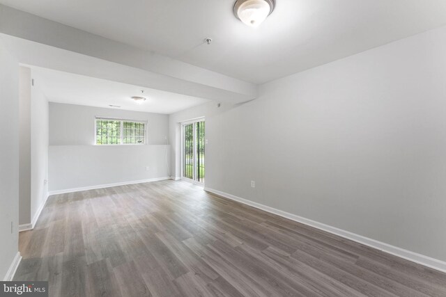 empty room featuring wood finished floors, baseboards, and fire sprinkler in ceiling