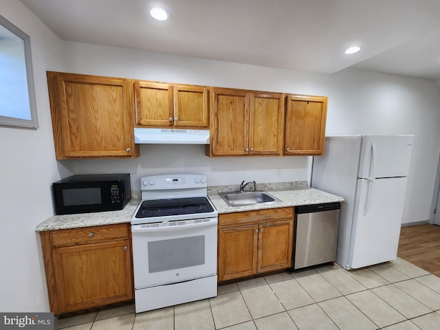 kitchen with a sink, brown cabinets, under cabinet range hood, and white appliances