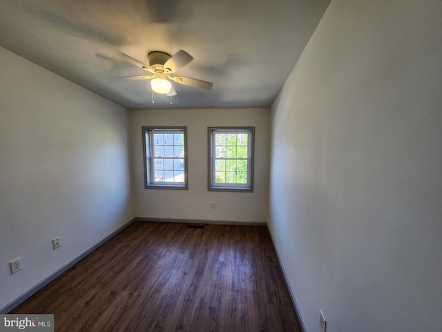 spare room featuring a ceiling fan, baseboards, and dark wood-style floors