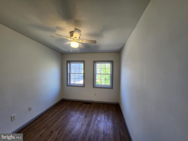 spare room featuring baseboards, a ceiling fan, and dark wood finished floors