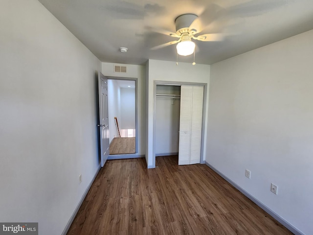 unfurnished bedroom featuring ceiling fan, visible vents, wood finished floors, baseboards, and a closet