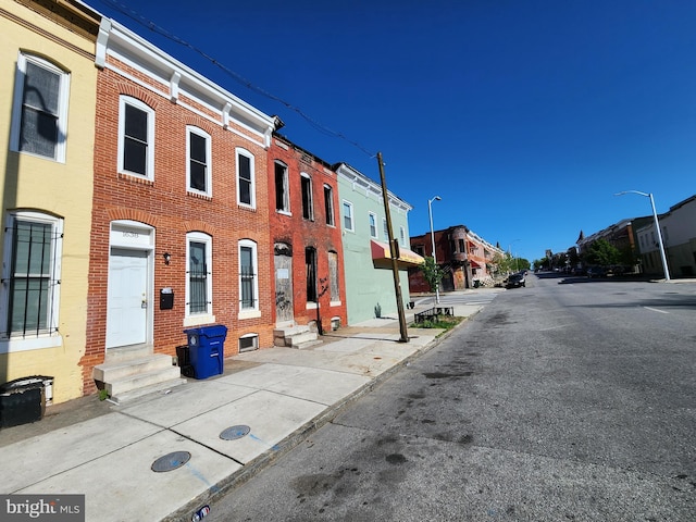 view of street with curbs, street lighting, a residential view, sidewalks, and entry steps