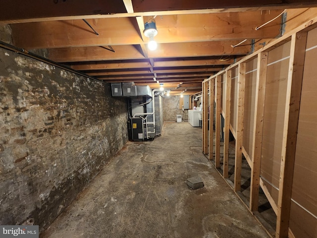unfinished below grade area with heating unit and washer / clothes dryer