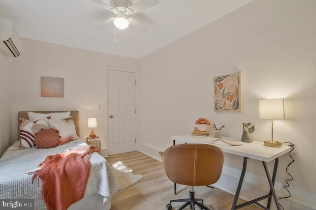 bedroom featuring an AC wall unit, a ceiling fan, and light wood finished floors