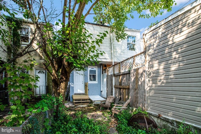back of house featuring brick siding and fence