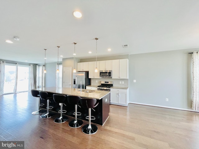 419 Foxglove Way Unit 106, Stafford, VA 22554 - kitchen with a center island with sink, a kitchen bar, a sink, light wood-style flooring, and stainless steel appliances