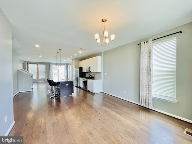 419 Foxglove Way Unit 106, Stafford, VA 22554 - kitchen featuring an inviting chandelier, a breakfast bar, dark wood finished floors, stainless steel appliances, and white cabinetry