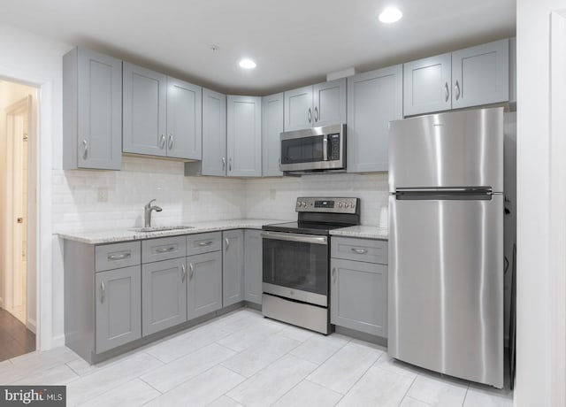 kitchen featuring a sink, appliances with stainless steel finishes, gray cabinets, and tasteful backsplash