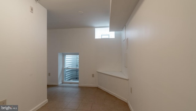 empty room featuring baseboards and light tile patterned flooring