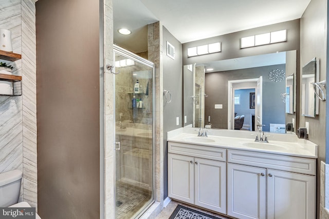 ensuite bathroom with a stall shower, double vanity, and toilet