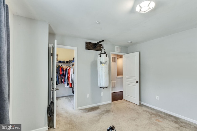 unfurnished bedroom featuring a walk in closet, carpet floors, baseboards, and a closet