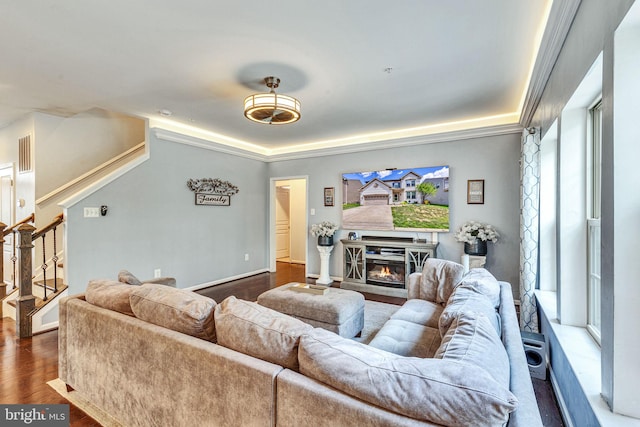 living area featuring stairway, healthy amount of natural light, dark wood-style floors, and a glass covered fireplace