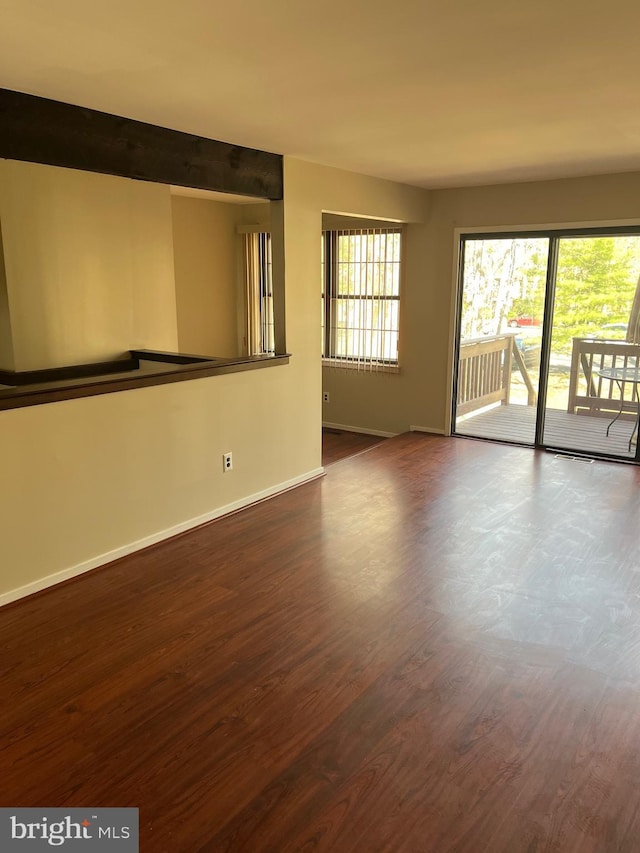 empty room featuring baseboards and dark wood finished floors