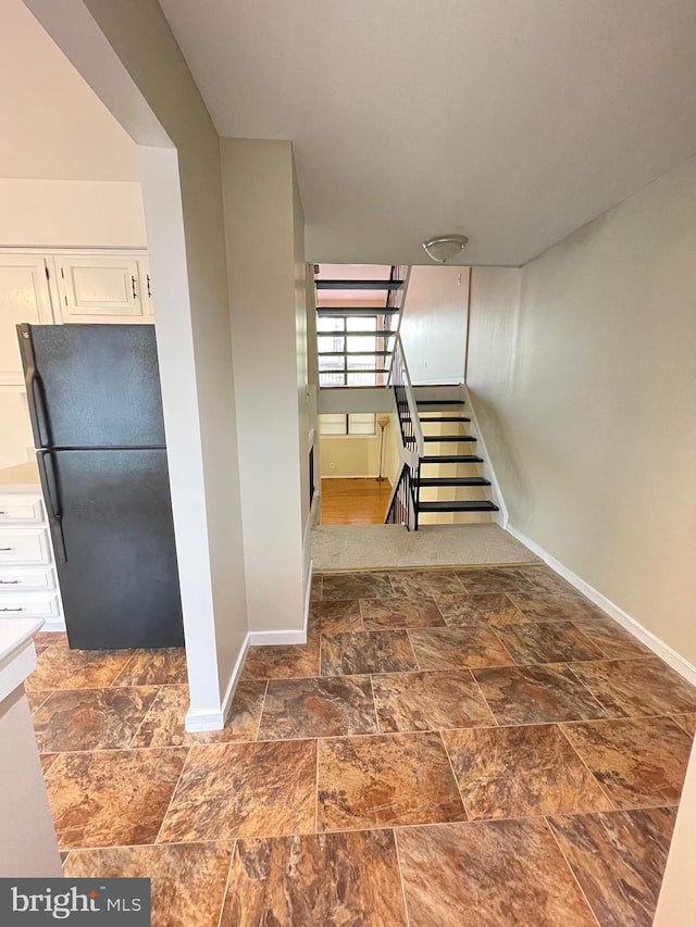 stairway with baseboards and stone finish floor
