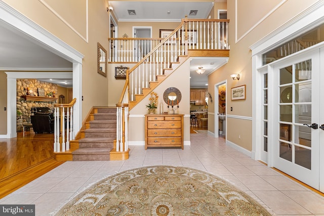 foyer entrance featuring tile patterned flooring, stairway, baseboards, a fireplace, and crown molding