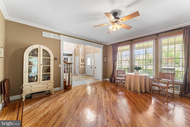 interior space featuring a ceiling fan, ornamental molding, light wood-type flooring, and baseboards