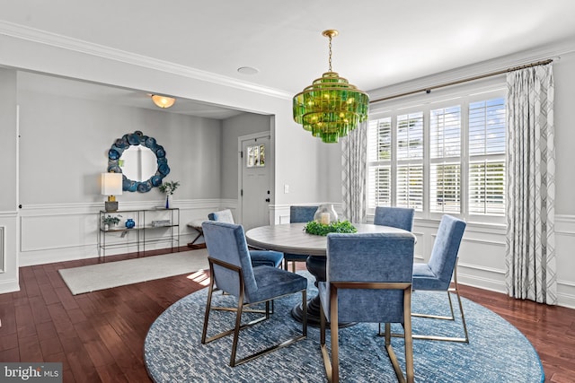 dining room with wood finished floors, a wainscoted wall, a decorative wall, and crown molding