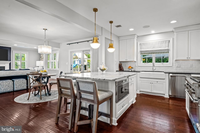kitchen with open floor plan, appliances with stainless steel finishes, a sink, backsplash, and recessed lighting
