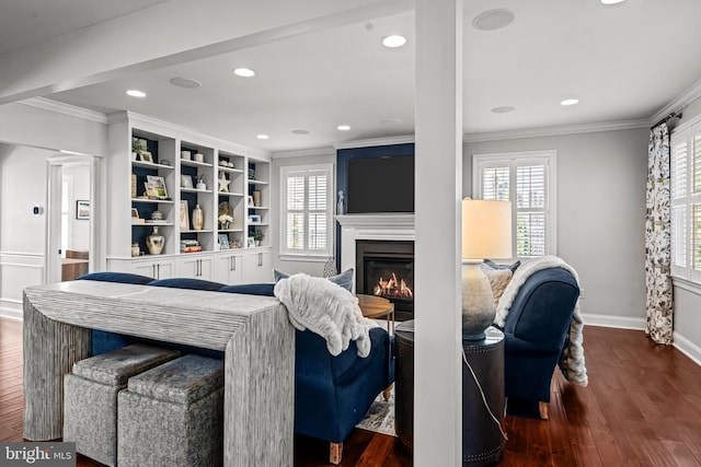 living room with crown molding, plenty of natural light, baseboards, wood finished floors, and a glass covered fireplace