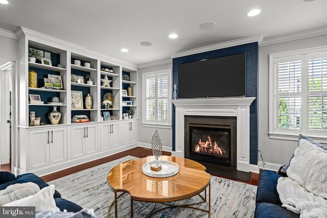 living room featuring wood finished floors, a fireplace with flush hearth, crown molding, recessed lighting, and baseboards