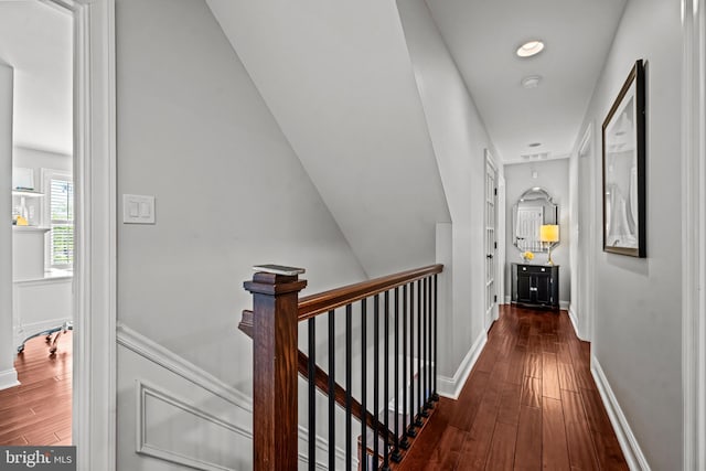 hall featuring hardwood / wood-style flooring, an upstairs landing, and baseboards