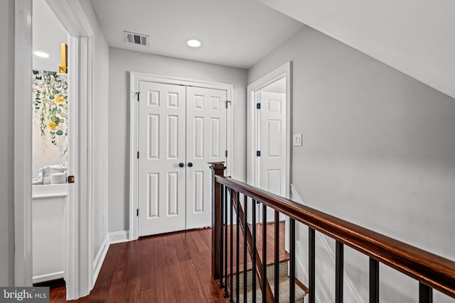 hallway featuring dark wood-style flooring, an upstairs landing, baseboards, and recessed lighting