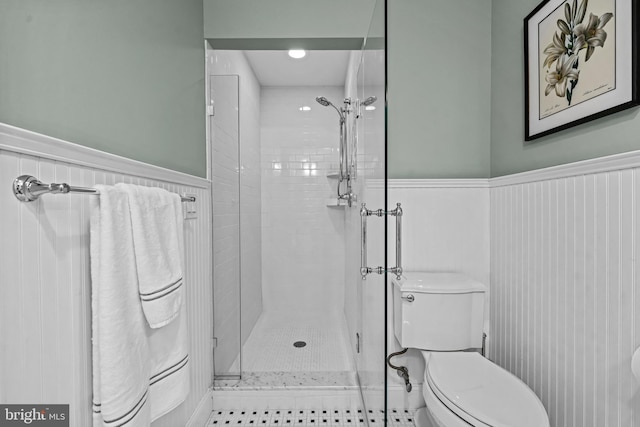 bathroom featuring wainscoting, tiled shower, and toilet