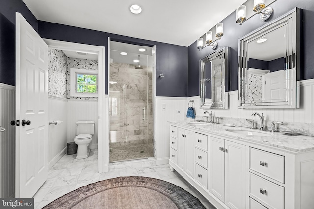 full bathroom with wainscoting, toilet, marble finish floors, a stall shower, and double vanity