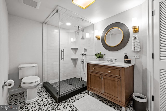 bathroom featuring a shower stall, toilet, vanity, tile patterned floors, and baseboards