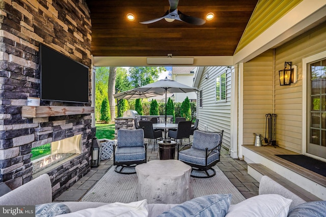 view of patio with an outdoor living space with a fireplace and a ceiling fan
