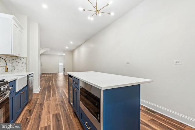 1107 S Divinity St, Philadelphia, PA 19143 - kitchen with appliances with stainless steel finishes, baseboards, dark wood-style flooring, and blue cabinetry