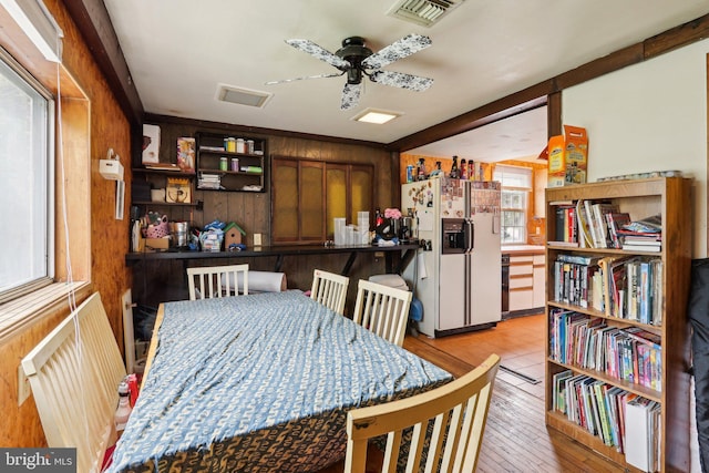 dining room featuring wooden walls, ceiling fan, and light wood finished floors