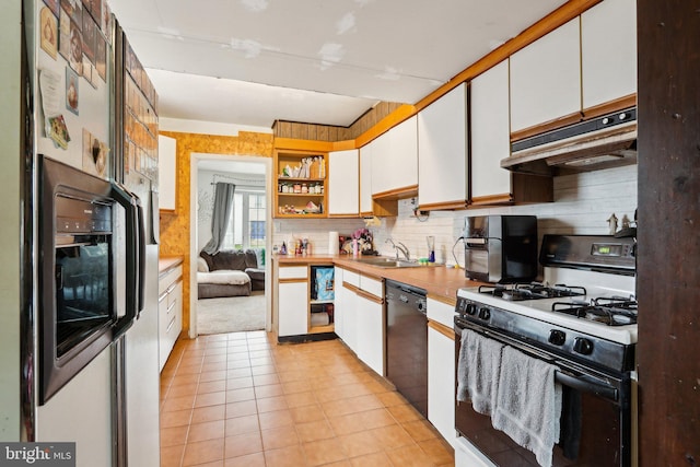 kitchen with gas range oven, refrigerator with ice dispenser, under cabinet range hood, a sink, and dishwasher