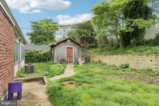 view of yard with a shed, central AC unit, and an outdoor structure