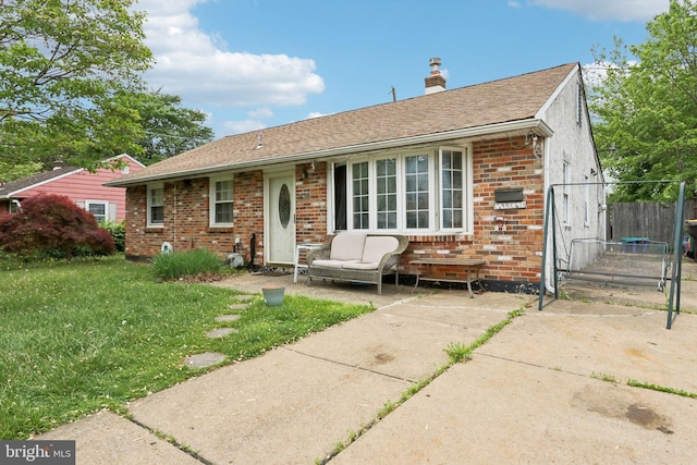 view of front of property with brick siding, a front lawn, a chimney, and a shingled roof