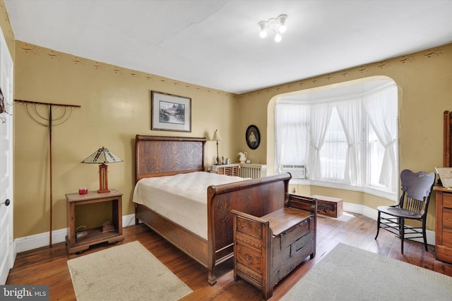 bedroom featuring baseboards, cooling unit, arched walkways, and wood finished floors
